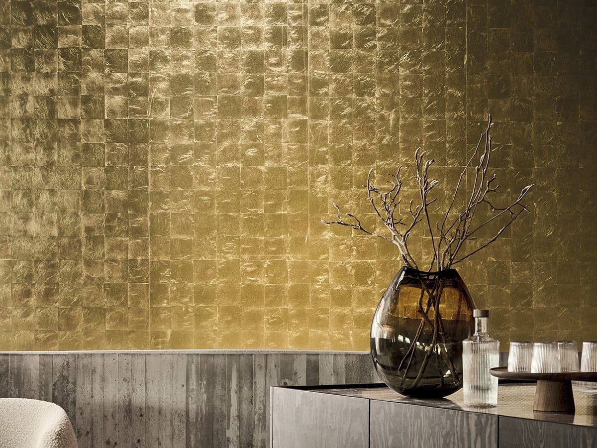 Metallic-Tapete — goldene Wand mit quadratischem Relief, davor ein Sideboard mit Vase