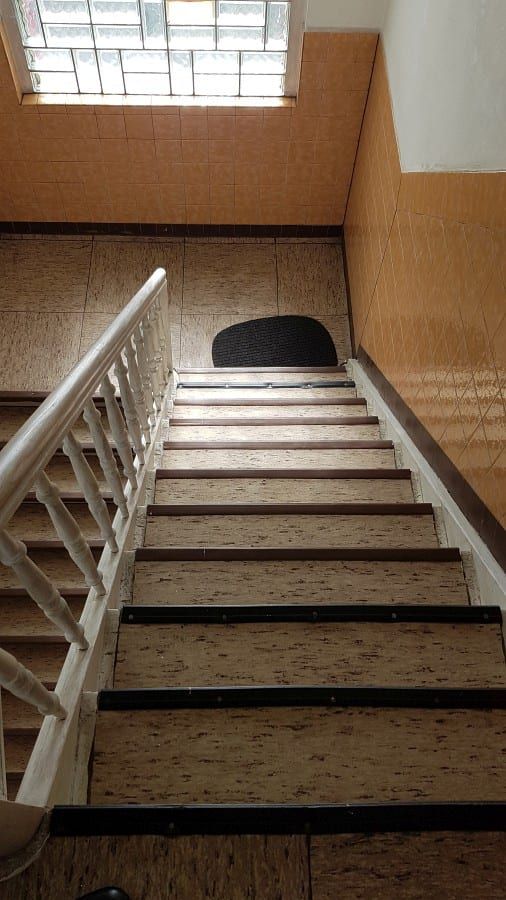 Treppenhaus mit ökologischem Linoleumbelag — Blick von oben auf den freigelegten Lauf, weißes Geländer