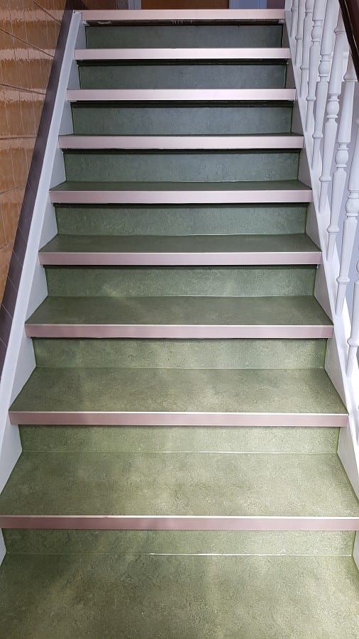 Treppenhaus mit ökologischem Linoleumbelag — belegter Lauf mit hellen Setzstufen, von unten gesehen