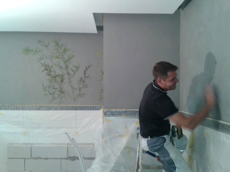 Badezimmer in Calce Colino, schwarz-silber — Handwerker beim Auftragen der Lasur über dem abgeklebten Fliesenspiegel