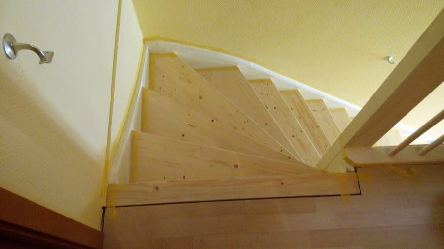 Holztreppe abgeschliffen und neu lackiert — Untersicht der gewendelten Stufen und der weißen Wange
