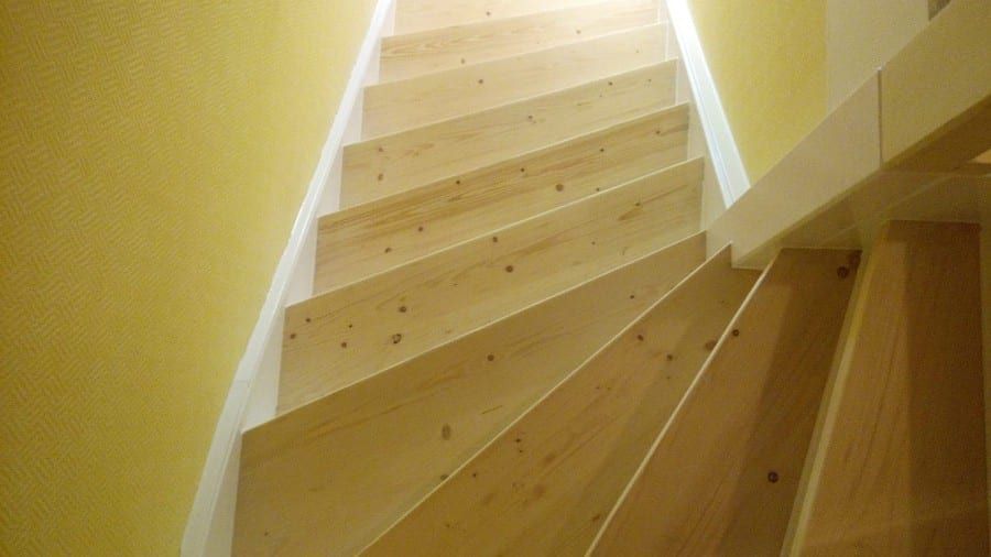 Holztreppe abgeschliffen und neu lackiert — Nahsicht der Trittstufen und der weißen Wange von schräg oben