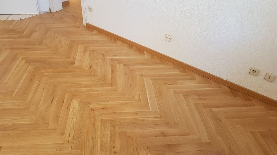 Eiche-Massivparkett im Fischgrätverband — Nahsicht des Musters an der weißen Wand