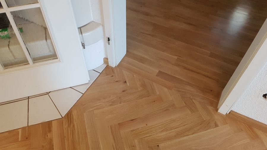 Eiche-Massivparkett im Fischgrätverband — Übergang zum hellen Fliesenboden am Fenster