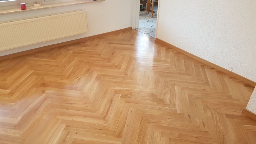 Eiche-Massivparkett im Fischgrätverband — leere Zimmerecke unter dem Fenster