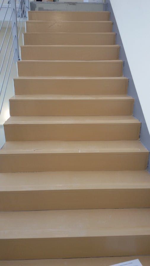 Fluchttreppenhaus mit Kautschukformtreppen — der Lauf zum hellen Zwischenpodest, Stufen bereits belegt