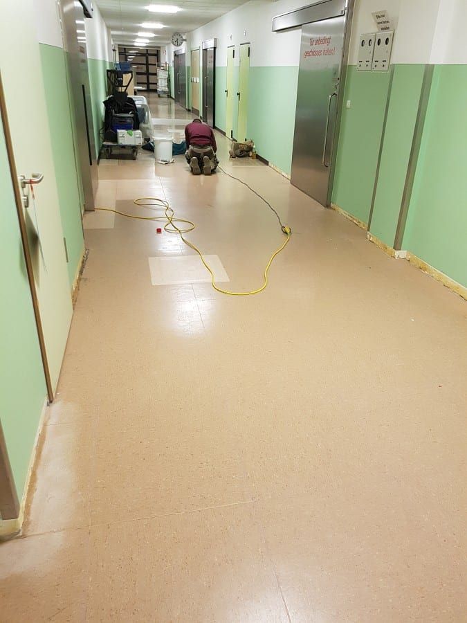 Alte Bodenbeläge im Gewerbe entfernt — Blick durch den ganzen Flur, Maschine am anderen Ende