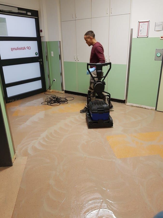 Alte Bodenbeläge im Gewerbe entfernt — Handwerker führt die Einscheibenmaschine über den Flur
