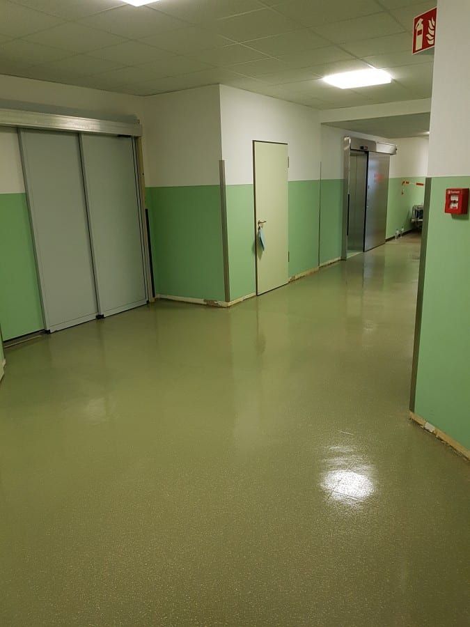 Untergrund für Industrieböden vorbereitet — Blick durch den grundierten Flur zum Notausgang
