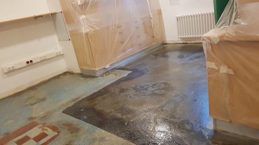 Neue Bodenbeschichtung, schichtweiser Aufbau — die frisch gespachtelte Fläche, noch feucht, entlang der Heizung