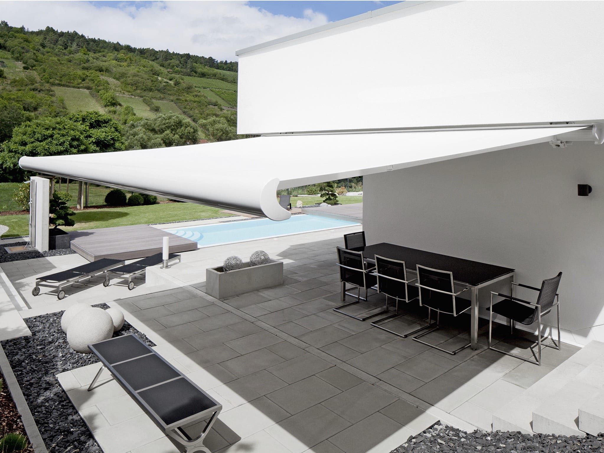 Gelenkarmmarkise über der Terrasse — weißes Tuch über der Terrasse am Pool, dunkle Sitzgruppe