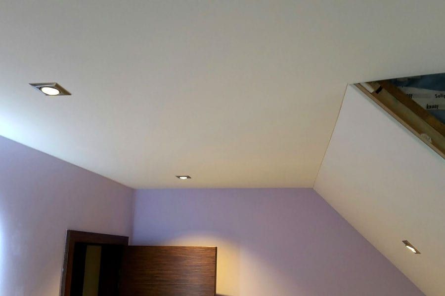 Badezimmer mit Holzdecke und Schräge — Deckenecke mit einem Einbaustrahler über der dunklen Tür