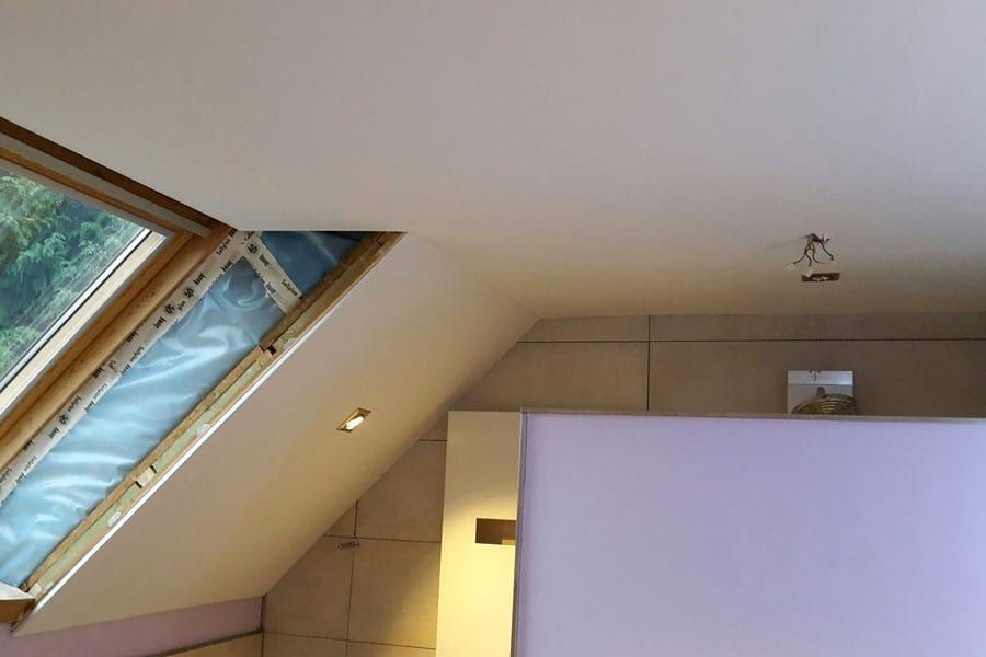 Badezimmer mit Holzdecke und Schräge — das Dachfenster sitzt in der Schräge, Strahler daneben