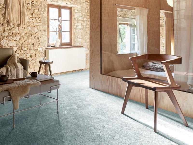 Teppichboden im Wohnraum — petrolfarbener Flor vor der Natursteinwand