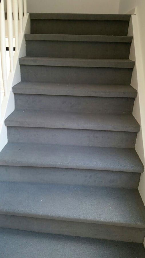 Holztreppe mit hochwertigem Textilbelag — Blick vom Antritt den grauen Lauf hinauf