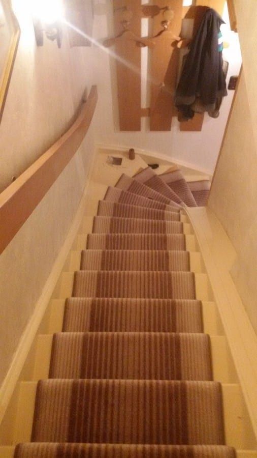 Treppenläufer auf gewendelter Holztreppe — Blick von oben den Lauf hinab, Läufer über alle Stufen