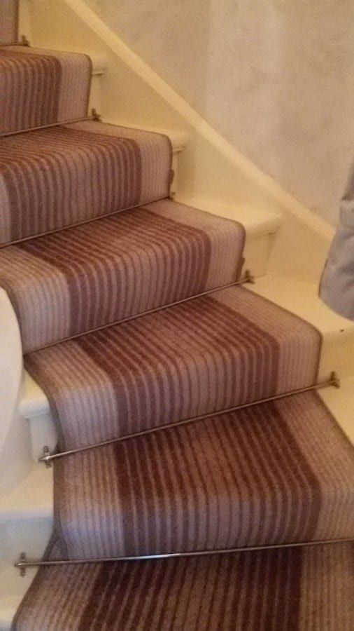 Treppenläufer auf gewendelter Holztreppe — die Läuferstangen auf den gewendelten Stufen von schräg oben